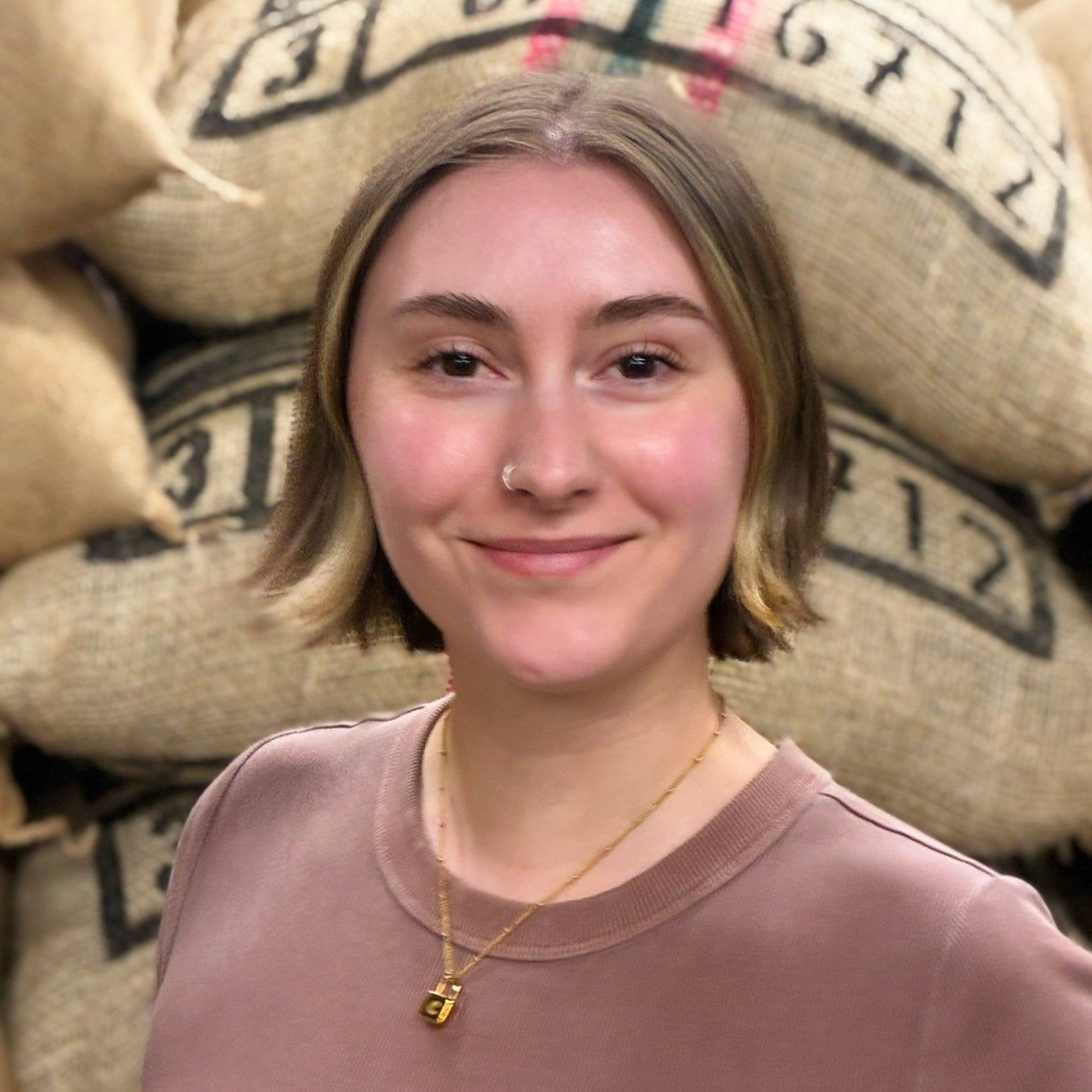 Person standing in front of stacked burlap coffee bags