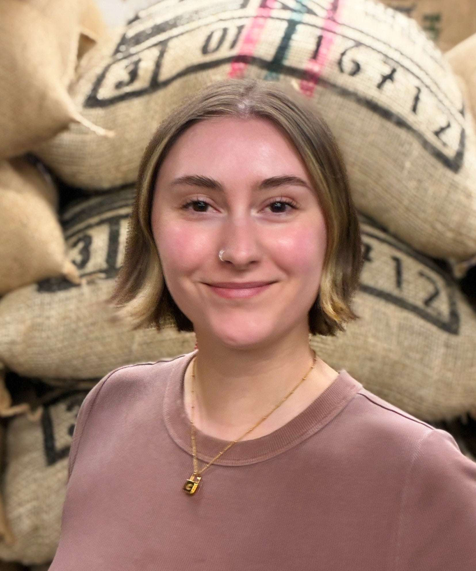 Person standing in front of stacked burlap coffee bags